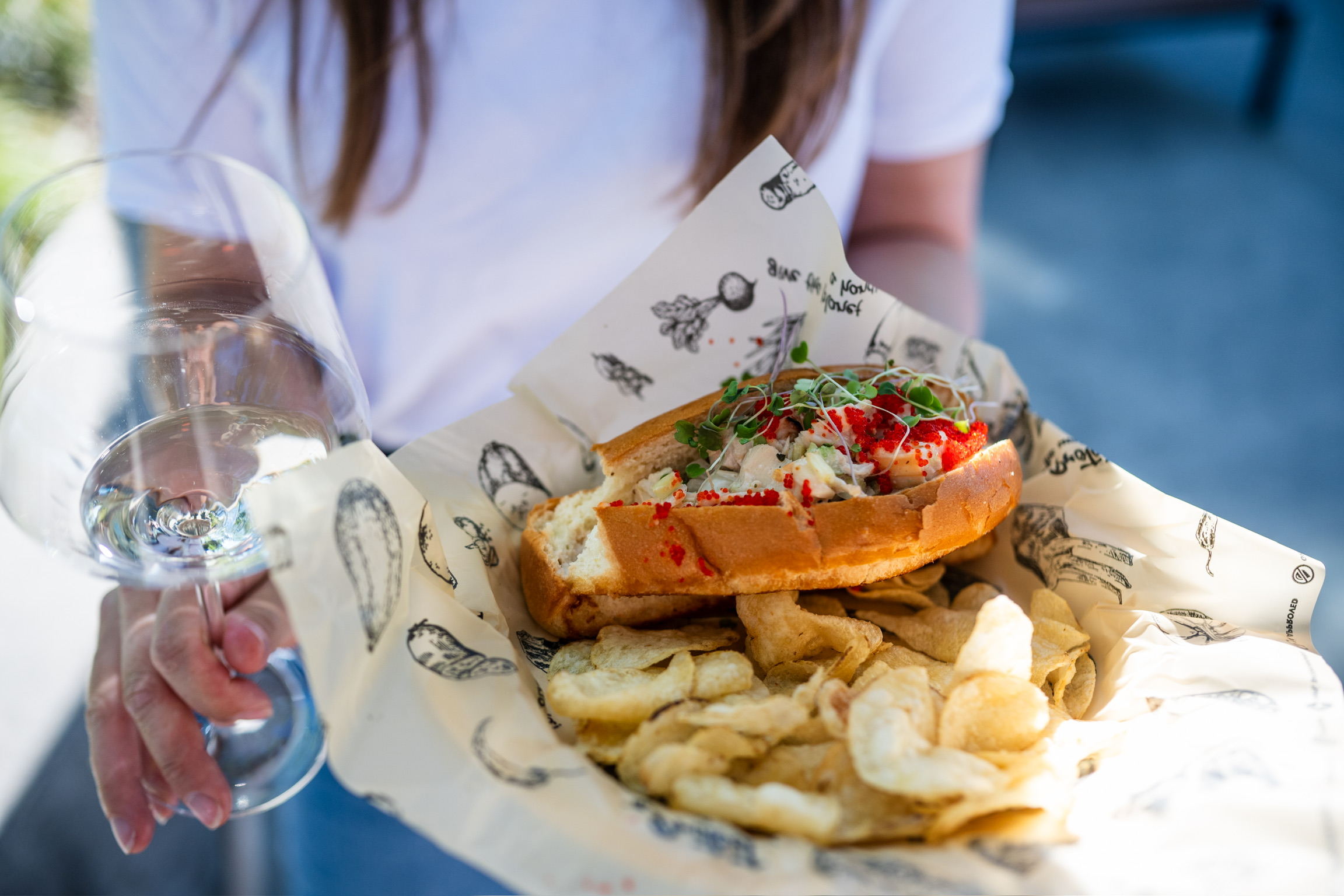 A person holding a meal and a glass of wine
