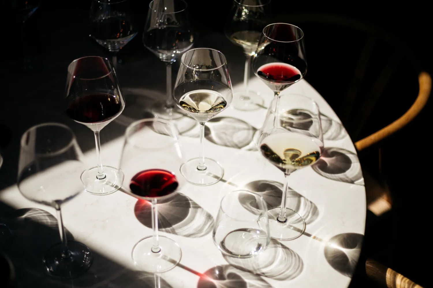 Multiple glasses with red and white wine standing on a table.