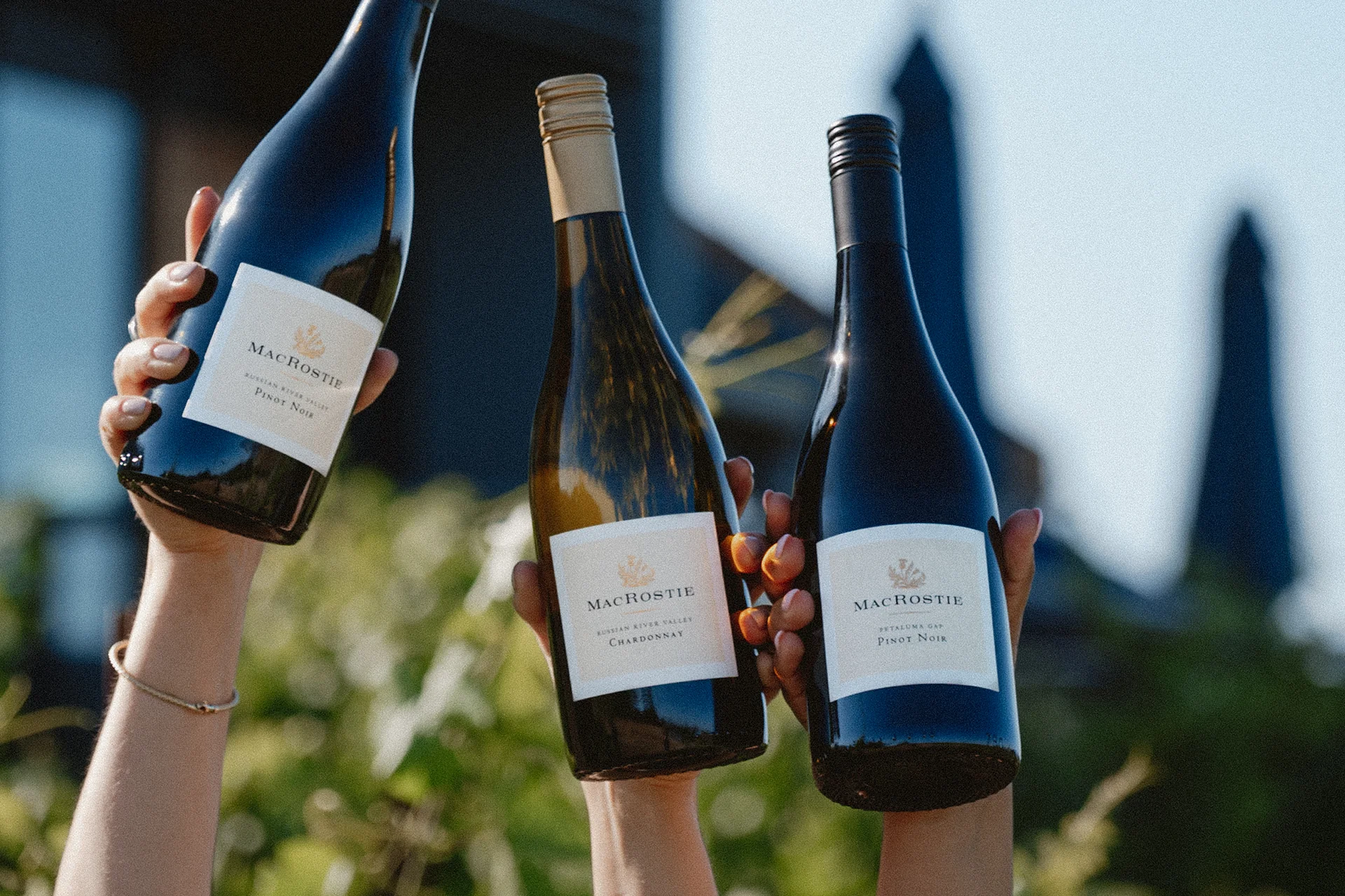 3 MacRostie wine bottles being held up by hands