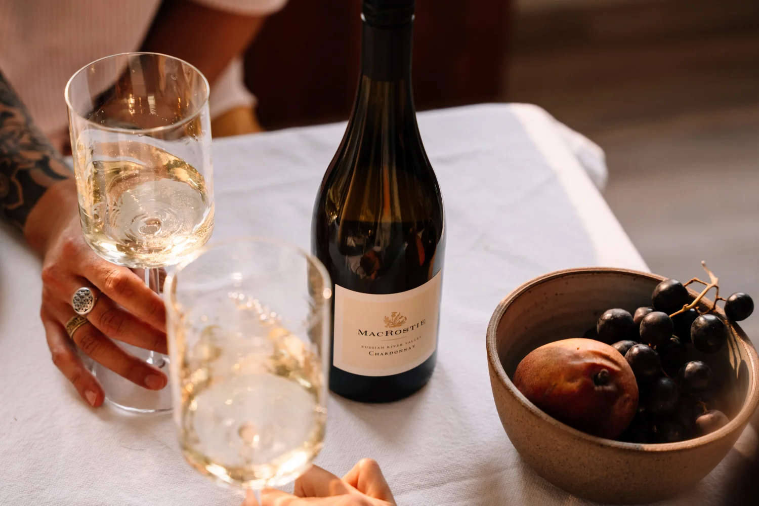 Bottle of Russian River Chardonnay on a table with people holding glasses of wine