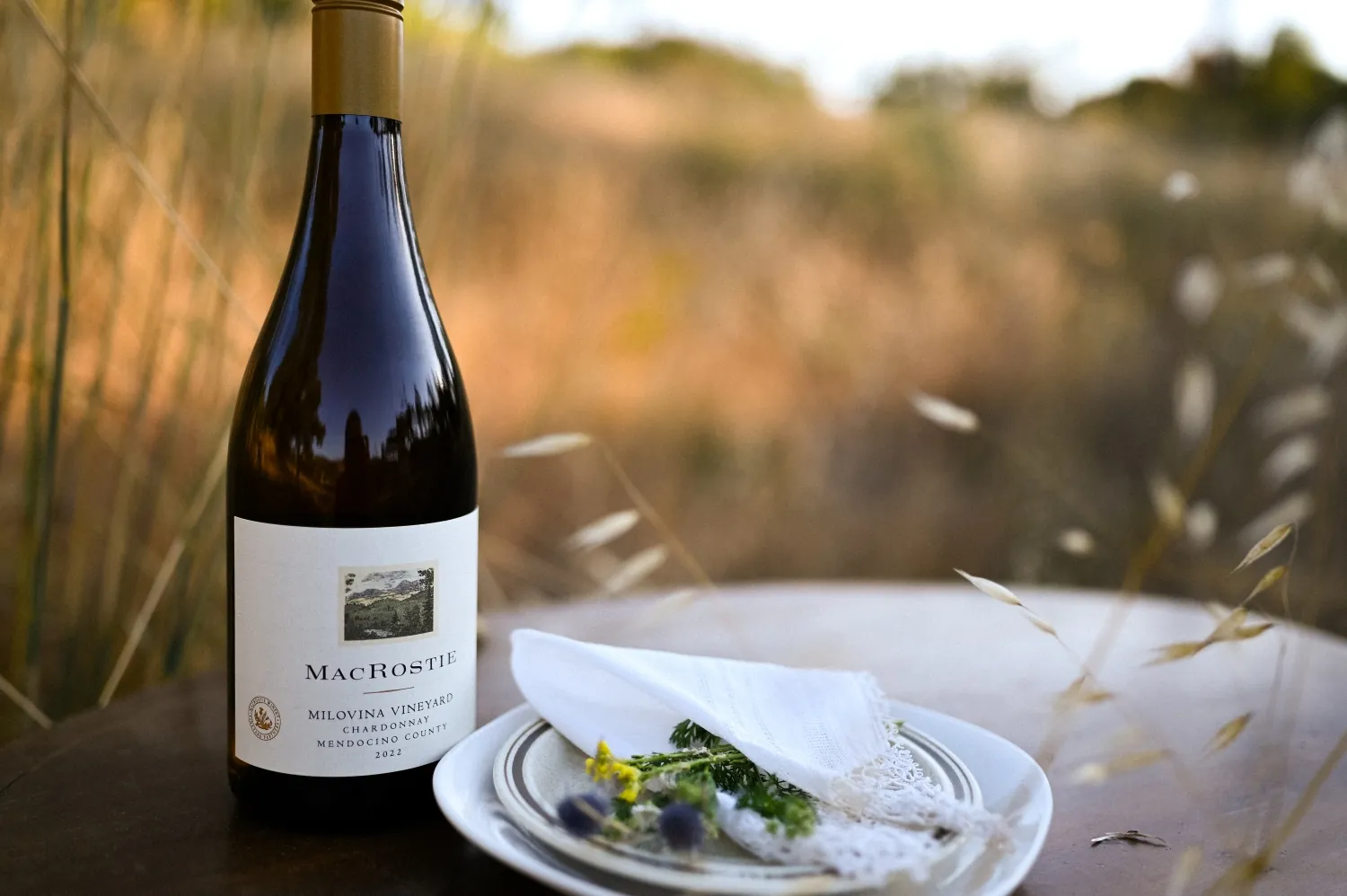 Bottle of MacRostie wine next to a plate with flowers on it.