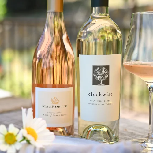 Bottle of MacRostie Rosé and Clockwise Sauvignon Blanc next to flowers and a glass of wine.