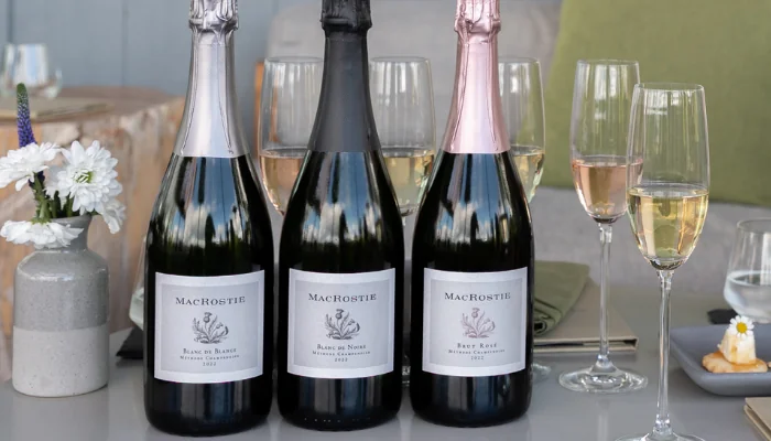 Lineup of MacRostie sparkling wines on a table next to glasses of wine, decor, and food pairings