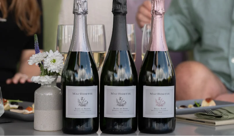 Bottles and glasses of MacRostie sparkling wine on a table next to food pairings and glasses of wine