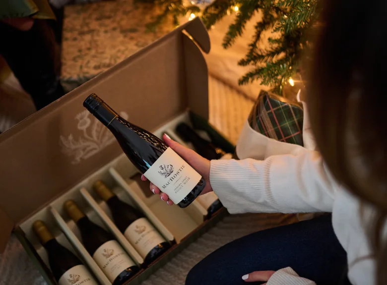 Opening wine gift under christmas tree
